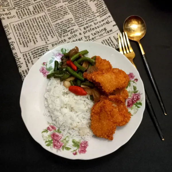 Siapkan nasi pada piring, tata nugget ayam goreng dan tambahkan buncis bawang.