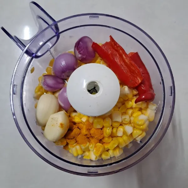 Masukkan jagung, bawang merah, bawang putih, cabe merah dan kunyit ke dalam food processor.