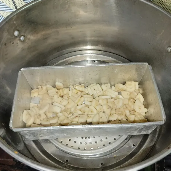 Masukkan loyang yang sudah dioles tipis dengan minyak goreng ke dalam kukusan yang sudah dipanaskan terlebih dahulu, lalu masukkan potongan pisang.