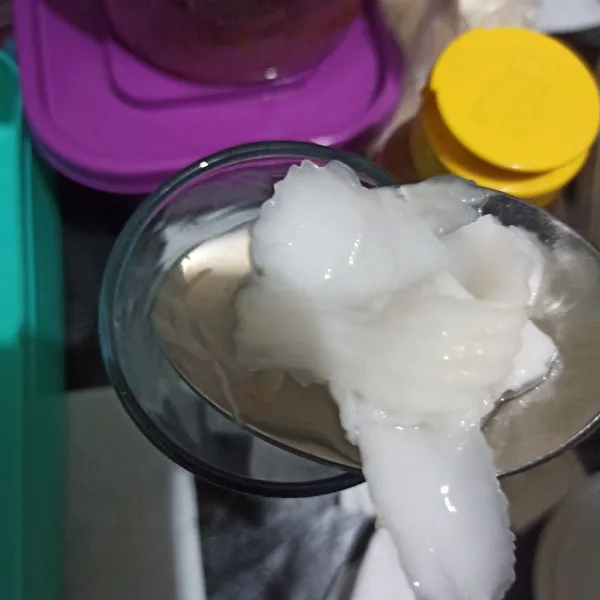 Siapkan gelas saji, beri es batu, kelapa muda, nata de coco.
