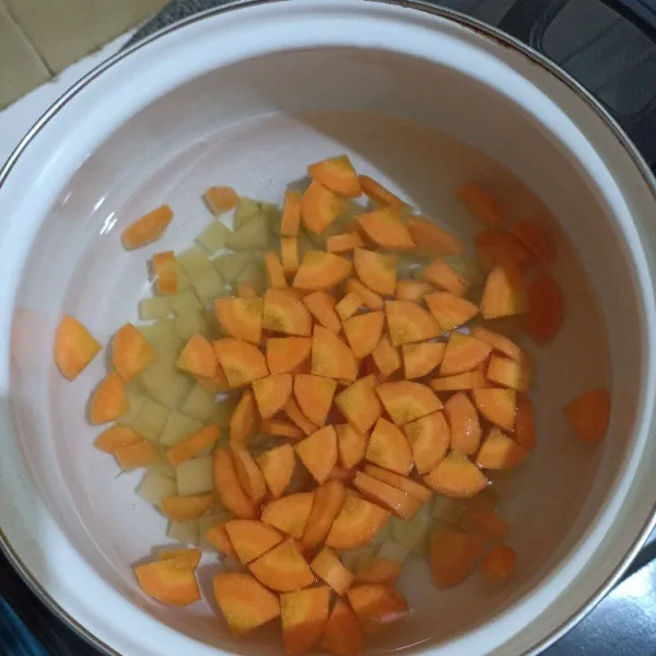 Didihkan air dalam panci, tuang potongan wortel dan kentangnya. Masak sampai mendidih.