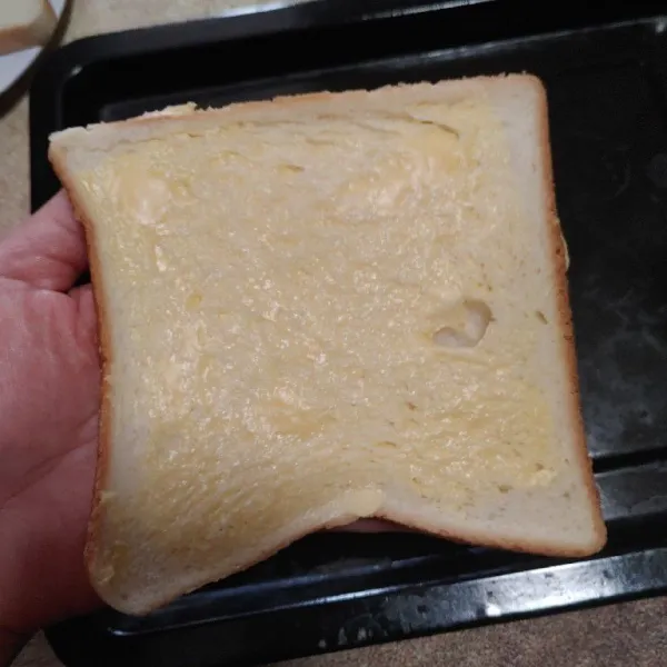 Olesi roti dengan margarin, tata diloyang (yang dioles bagian bawah) agar saat matang roti menjadi renyah.