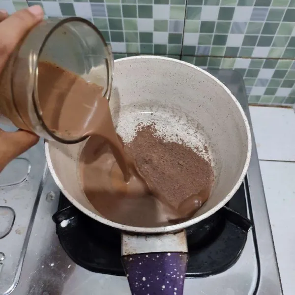 Setelah itu salin jelly coklat dan coklat bubuk ke dalam wajan, kemudian tuang blenderan kurma serta sisa susu coklat full cream. Aduk rata. Kemudian nyalakan apinya.