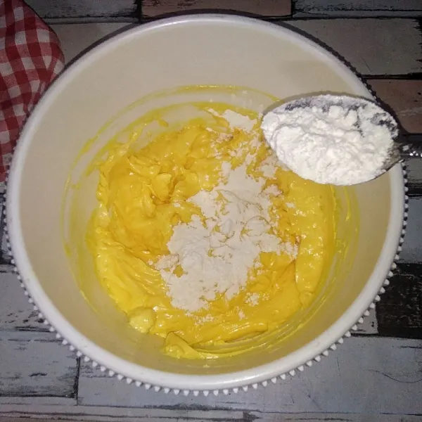 Masukkan susu bubuk, aduk hingga merata kemudian masukkan pewarna kuning telur, aduk rata kembali. Lalu masukkan tepung terigu sedikit demi sedikit hingga adonan kalis dan bisa di bentuk