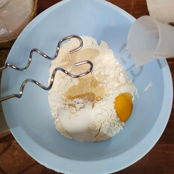 Masukkan tepung terigu, gula, ragi instan, kuning telur, santan dan air. Mikser hingga tercampur rata.