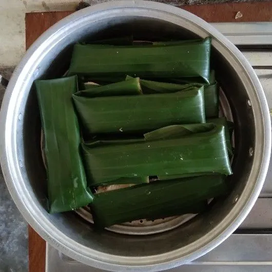 Siapkan daun pisang. Letakkan ikan mujair, ratakan bumbu halus diatasnya dan taburi bumbu rajang yang telah disiapkan.