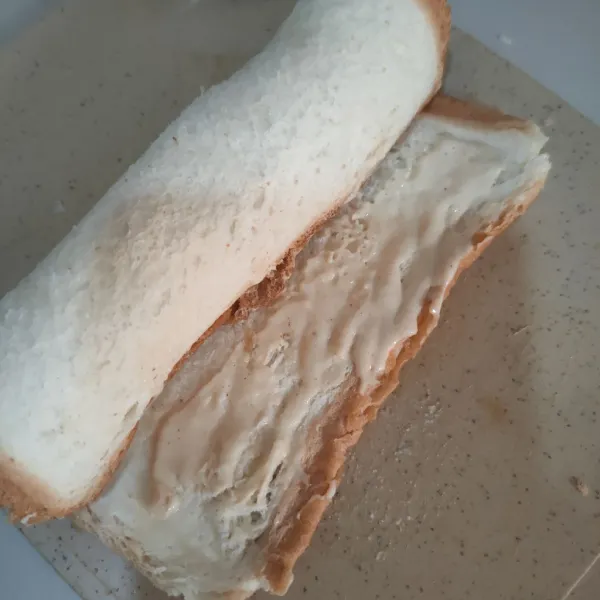 Gulung sosis dengan roti tawar, beri larutan tepung di bagian ujung roti tawar untuk merekatkan.
