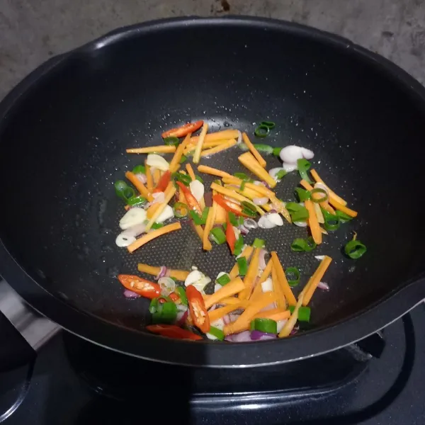 Masukkan irisan wortel, cabai dan daun bawang.