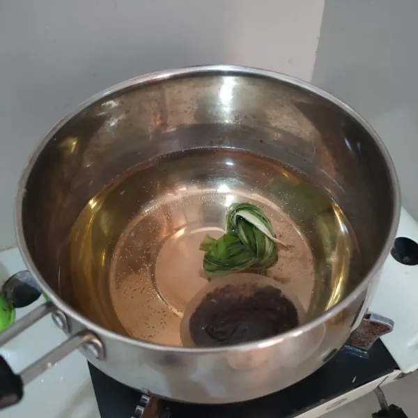 Masukkan ke pan 500 ml air, daun pandan, kantung teh dan gula palm. Masak hingga mendidih.