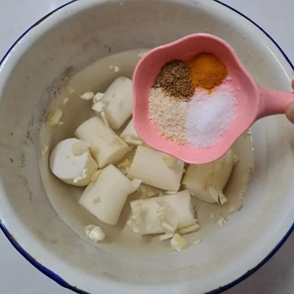 Masukkan singkong dalam panci. Beri air, bawang putih, kaldu jamur, garam, ketumbar bubuk dan kunyit bubuk. Aduk sampai rata.