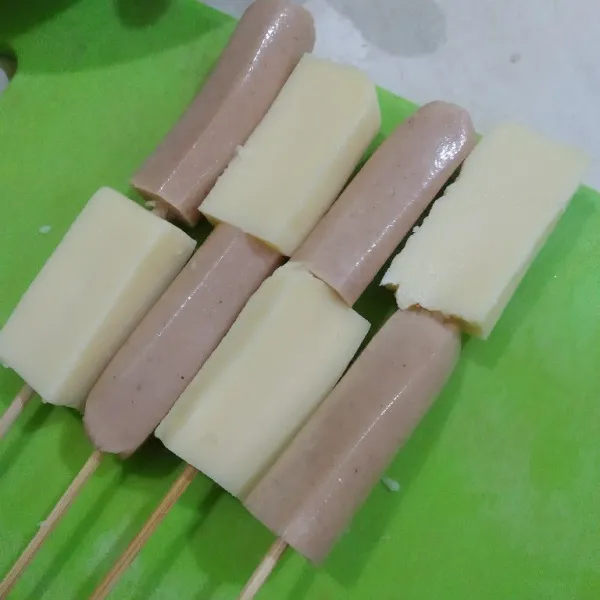 Potong sosis dan keju mozzarella sesuai selera, lalu tusuk dengan tusukan sate
