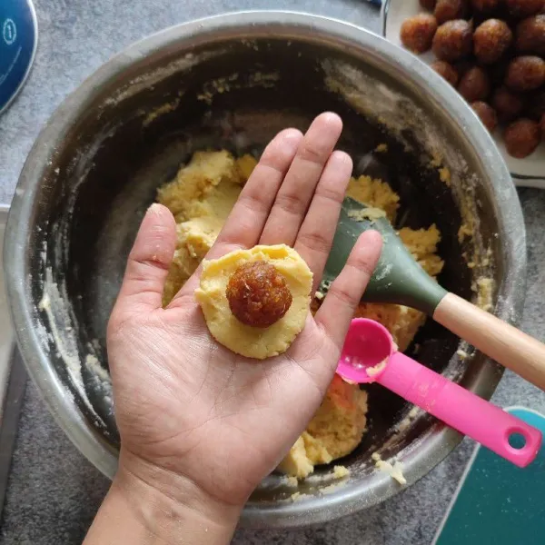 Timbang adonan 15 gram dan bahan isian nastar 10 gram. Pipihkan adonan kulit lalu isi dengan selai nanas.