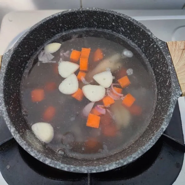 Masukkan irisan bawang merah, bawang putih dan wortel. Rebus hingga wortel empuk.