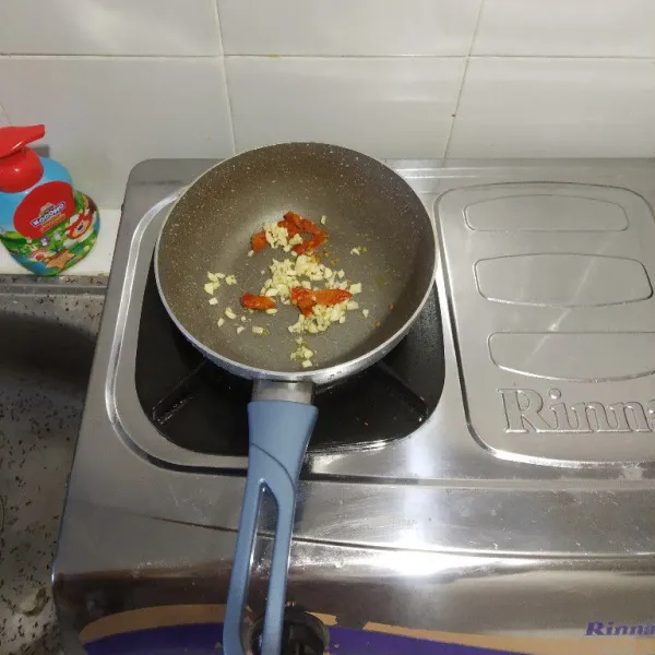Tumis bawang putih dan cabai rawit merah hingga harum.