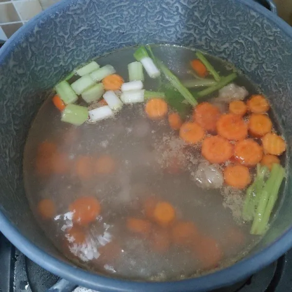 Masukkan sayur wortel, batang daun seledri dan irisan daun bawang. Masak sampai wortel empuk dan kuah harum.