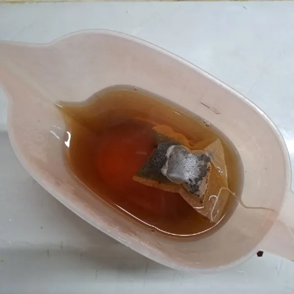 Seduh teh celup dengan air panas sampai berubah warna kemerahan.