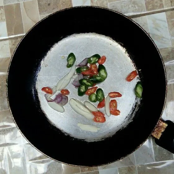 Tumis bawang putih, bawang merah, cabe rawit merah, dan cabe hijau hingga harum.