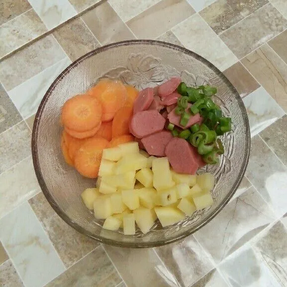 Iris sosis, kentang, wortel, dan daun bawang.