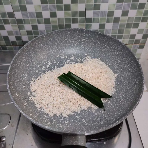 Masukan beras ketan yang sudah direndam dan dibilas ke dalam wajan anti lengket. Tambahkan daun pandan.