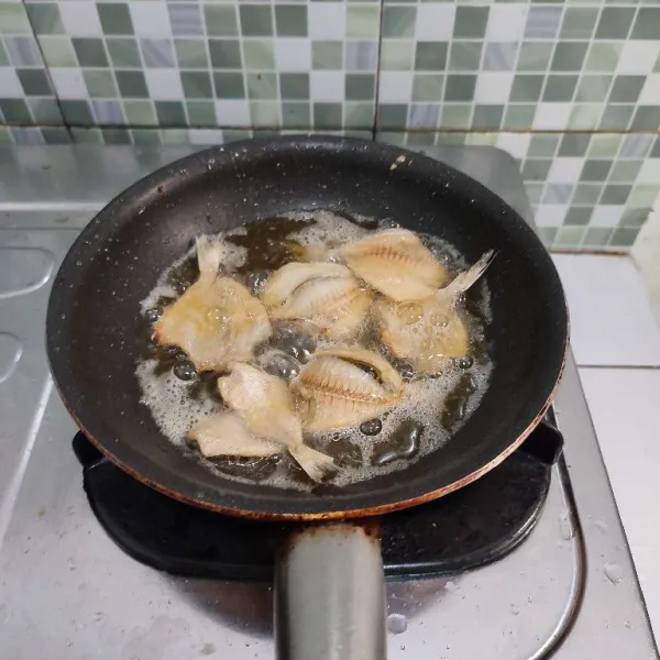 Cuci bersih ikan asin, lalu goreng dalam minyak panas dengan api kecil hingga garing.