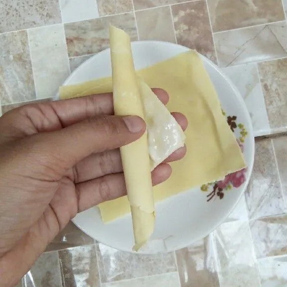 Gulung kulit pangsit. Rekatkan dengan bahan perekat.