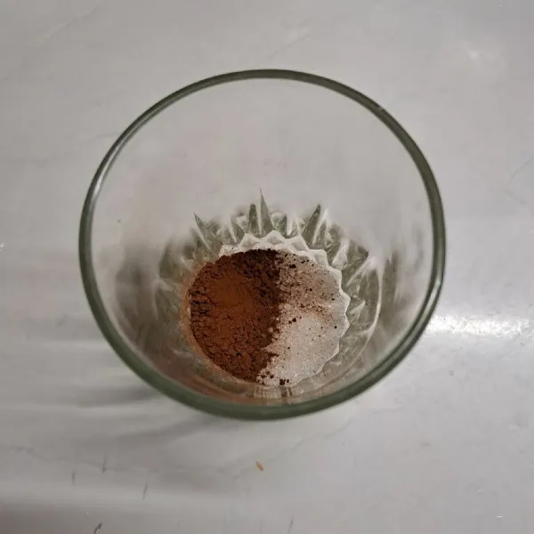 Tuang kopi bubuk dan gula pasir ke dalam gelas.