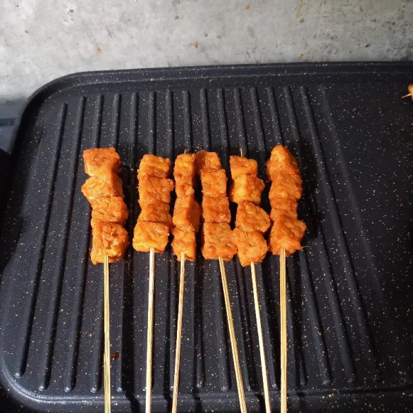 Tusuk tempe dengan tusuk sate. Kemudian panggang sate tempe.