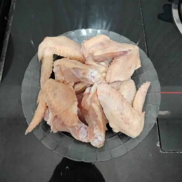 Potong sayap ayam menjadi 2 bagian, lalu lumuri dengan air jeruk nipis, kemudian cuci dan bilas hingga bersih.