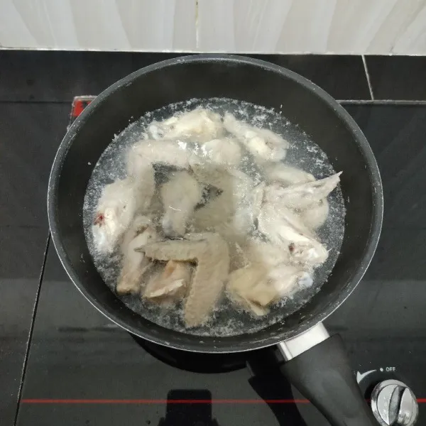 Kemudian rebus sayap ayam dengan air secukupnya hingga mendidih. Lalu tiriskan ayam dan buang air rebusannya.