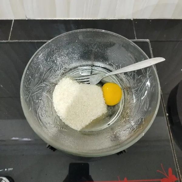 Masukkan telur dan gula pasir ke dalam mangkuk, lalu kocok hingga gula larut.