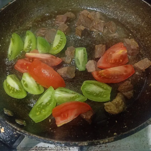 Siapkan wajan lalu masukkan minyak. Setelah panas minyak masukkan irisan tomat dan daging. Oseng sampai setengah matang dagingnya.