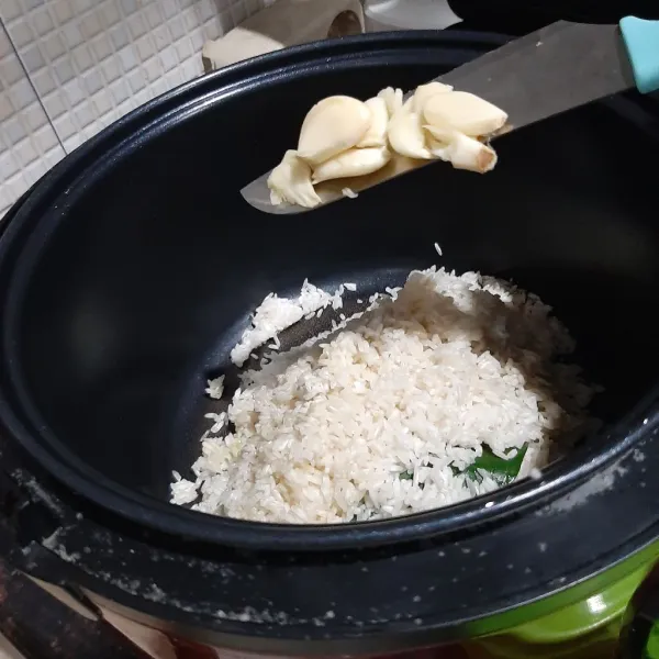 Masukan beras dalam rice cooker dan tambahkan bawang putih geprek.