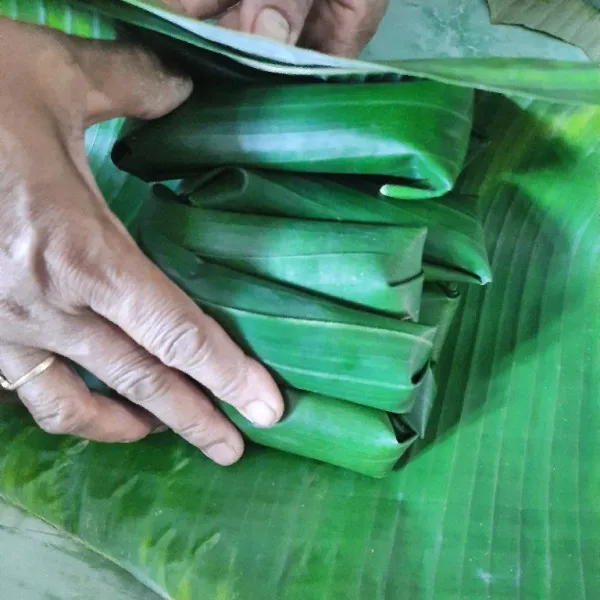 Bungkus kembali dengan daun yang lebih besar, isi sekitar 10 lepet