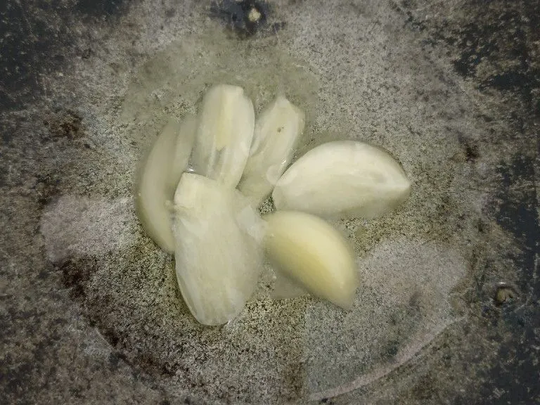 Panaskan wajan, tuang minyak sampai panas, dan masukkan bawang putih yang sudah dipotong tipis.