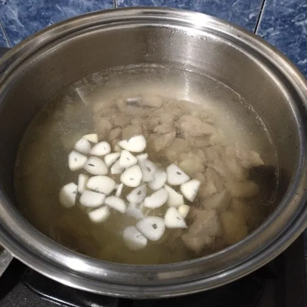 Didihkan air dalam panci. Lalu masukkan dada ayam dan irisan bawang putih. Masak sekitar 5 menit.