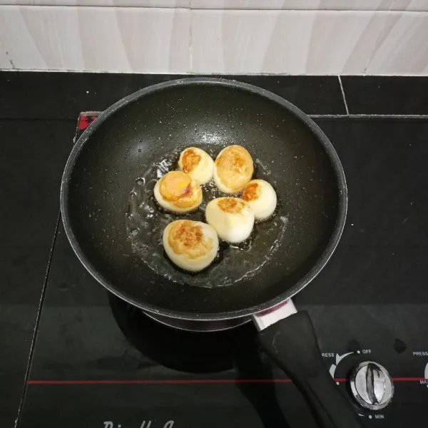 Rebus telur hingga matang, lalu kupas dan goreng hingga berkulit. Angkat.