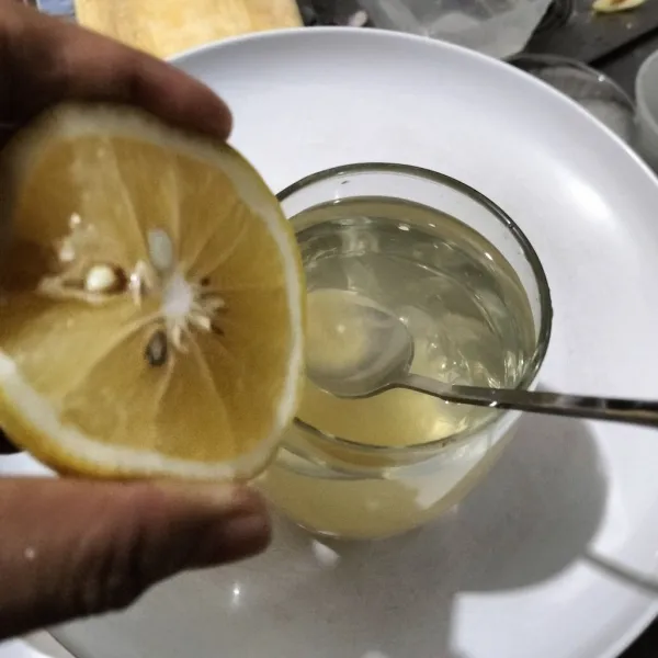 Peras jeruk lemon masukkan ke dalam gelas madu.