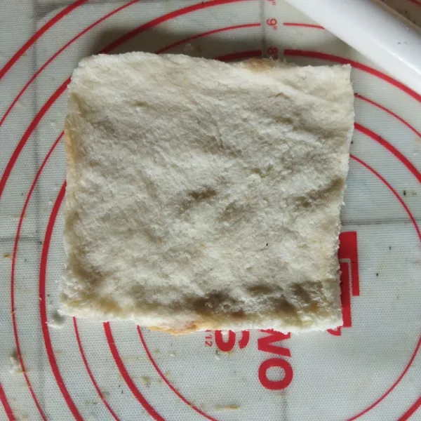 Celupkan roti tawar ke dalam susu sebentar saja, lalu pipihkan roti dengan rolling pin atau tangan.