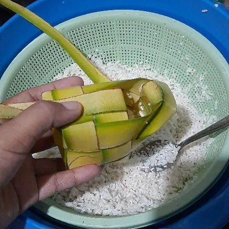 Ambil selongsong ketupat kemudian beri isian beras 1/2 bagian saja, kalo kebanyakan jadi keras