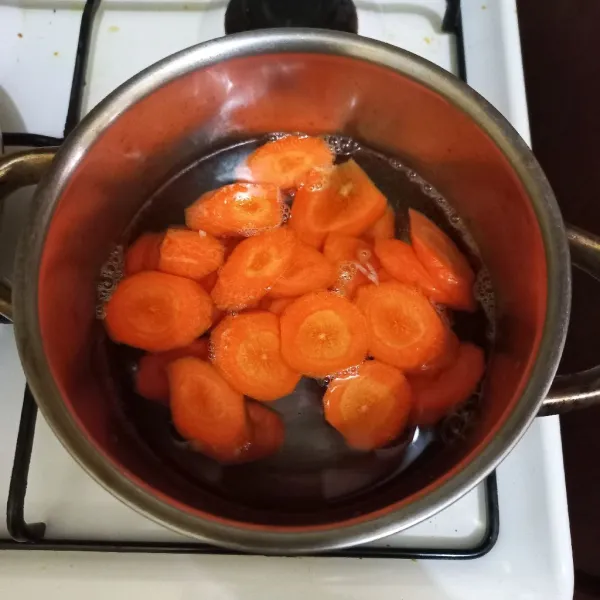 Didihkan air dalam panci, masukkan irisan wortel.