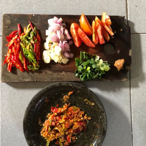 Kemudian iris bawang merah, bawang putih, tomat, beberapa cabai merah keriting dan cabai rawit. Lalu sisihkan beberapa bumbu seperti bawang merah, bawang putih, cabai merah, dan rawit kemudian ulek kasar.