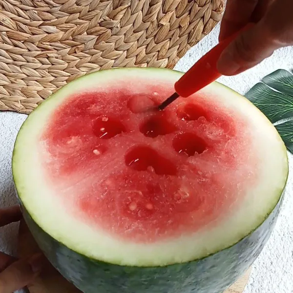 Belah semangka jadi dua bagian kemudian kerok buahnya.