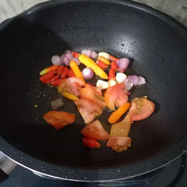 Goreng cabai rawit, bawang merah, bawang putih, tomat dan terasi sampai matang.