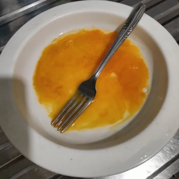 Kocok lepas telur dengan garpu.
