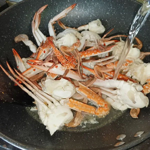 Masukkan kepiting dan aduk-aduk sampai berubah warna, kemudian tuang air.