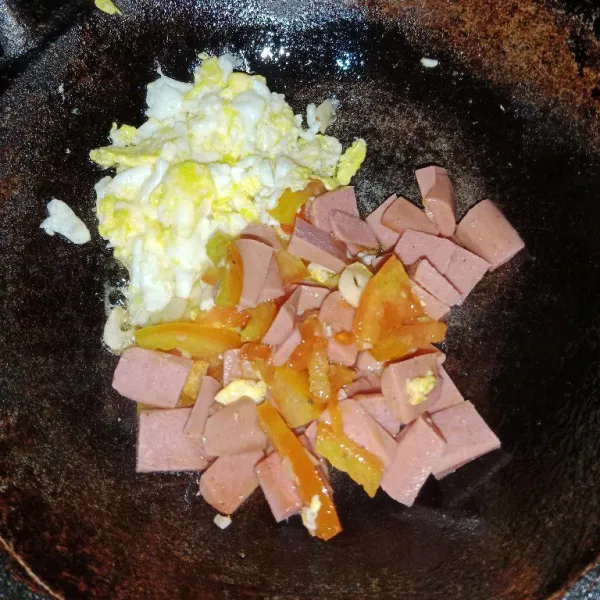 Sisihkan telur dipunggir wajan lalu tumis bawang putih, tomat dan sosis sampai layu.