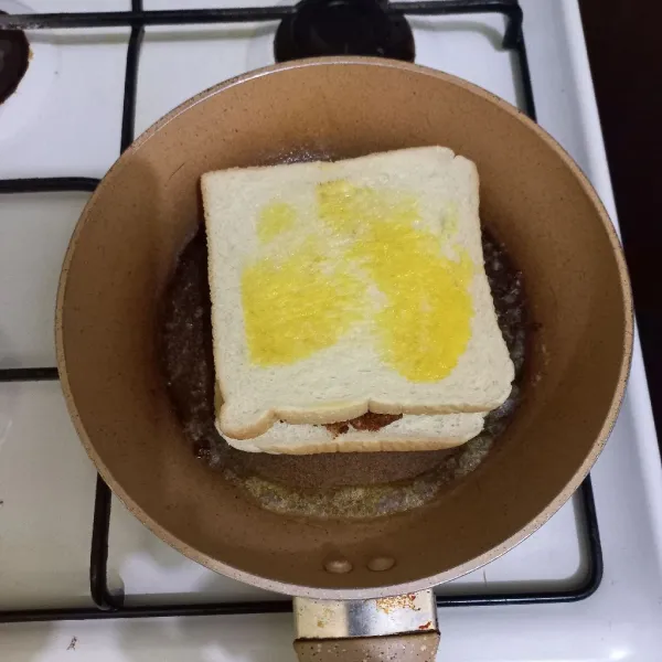 Tutup kembali dengan roti tawar, olesi permukaan roti dengan margarin.