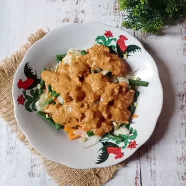 Tata sayuran di piring saji, kemudian siram dengan bumbu kacang.