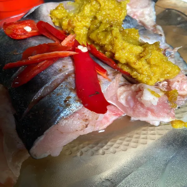 Masukkan tumisan bumbu halus, irisan cabe merah, air asam jawa, dan terasi kedalam potongan ikan.