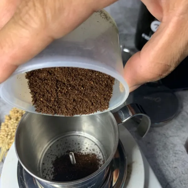 Tuang serbuk kopi ke gelas vietnam drip